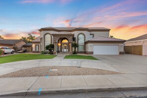 A two-story house with a front entrance, a garage, and a driveway. - Luxury 6BR Retreat - Pool, BBQ, Theater and Games (Mesa)