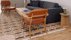 A modern living room with a grey sofa, wooden chairs, a small round table, and a patterned rug. - Chic city pad - Handpainted art - Great location by Daniel&Jacob's (København)