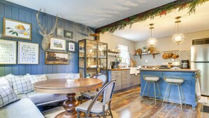 A cozy kitchen with a dining area, wooden flooring, and a blue accent wall.