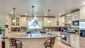 A spacious kitchen with a large island, two bar stools, a stainless steel oven, and a microwave. - Spacious Escape Near Mesa Verde National Park! (Mancos)
