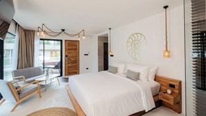 A modern bedroom with a large bed, a wooden nightstand, a bedside table, a sofa, and a small table with a lamp. - Samaraya Wellness Resort (Koh Samui)