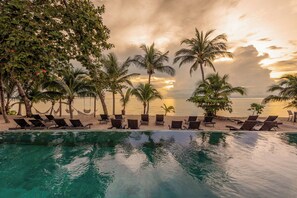 A poolside area with lounge chairs and palm trees, overlooking a beach and ocean. - Samaraya Wellness Resort (Koh Samui)