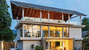 A modern two-story house with a large balcony, a thatched roof, and a well-maintained garden. - Samaraya Wellness Resort (Koh Samui)
