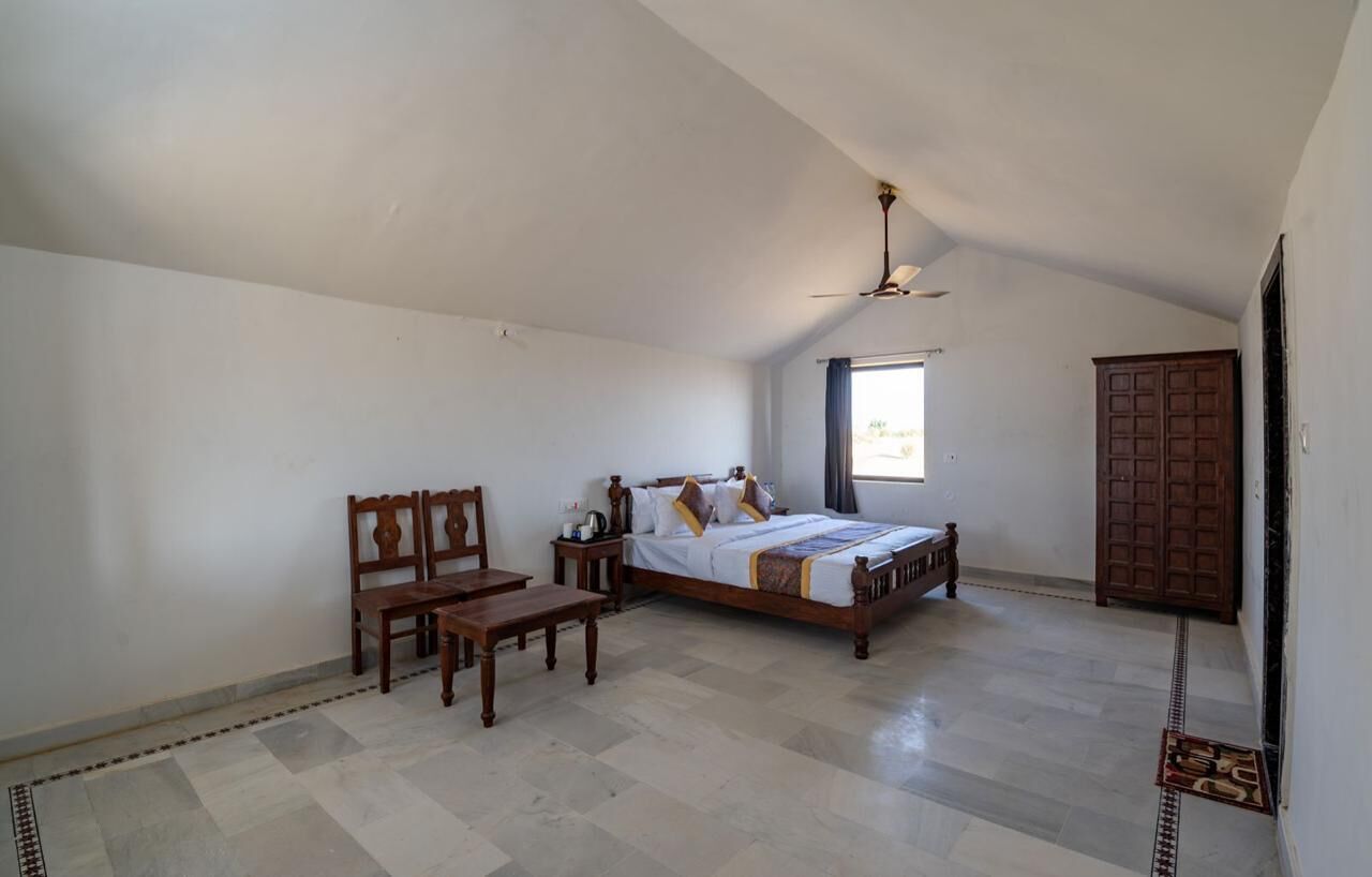 A bedroom with a bed, wooden furniture, a ceiling fan, and a window.