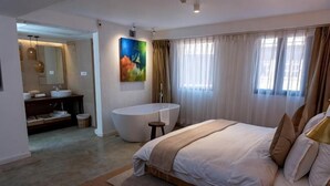A modern bedroom with a large bed, a bathtub, and a separate bathroom with a vanity. - The Nanee (Bhaktapur)