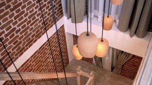A staircase with hanging pendant lights, a brick wall, and a wooden floor. - The Nanee (Bhaktapur)