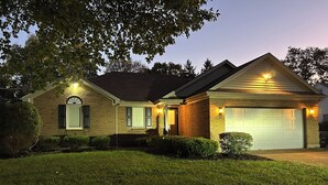 A two-story house with a garage, a covered front porch, and a well-maintained lawn.