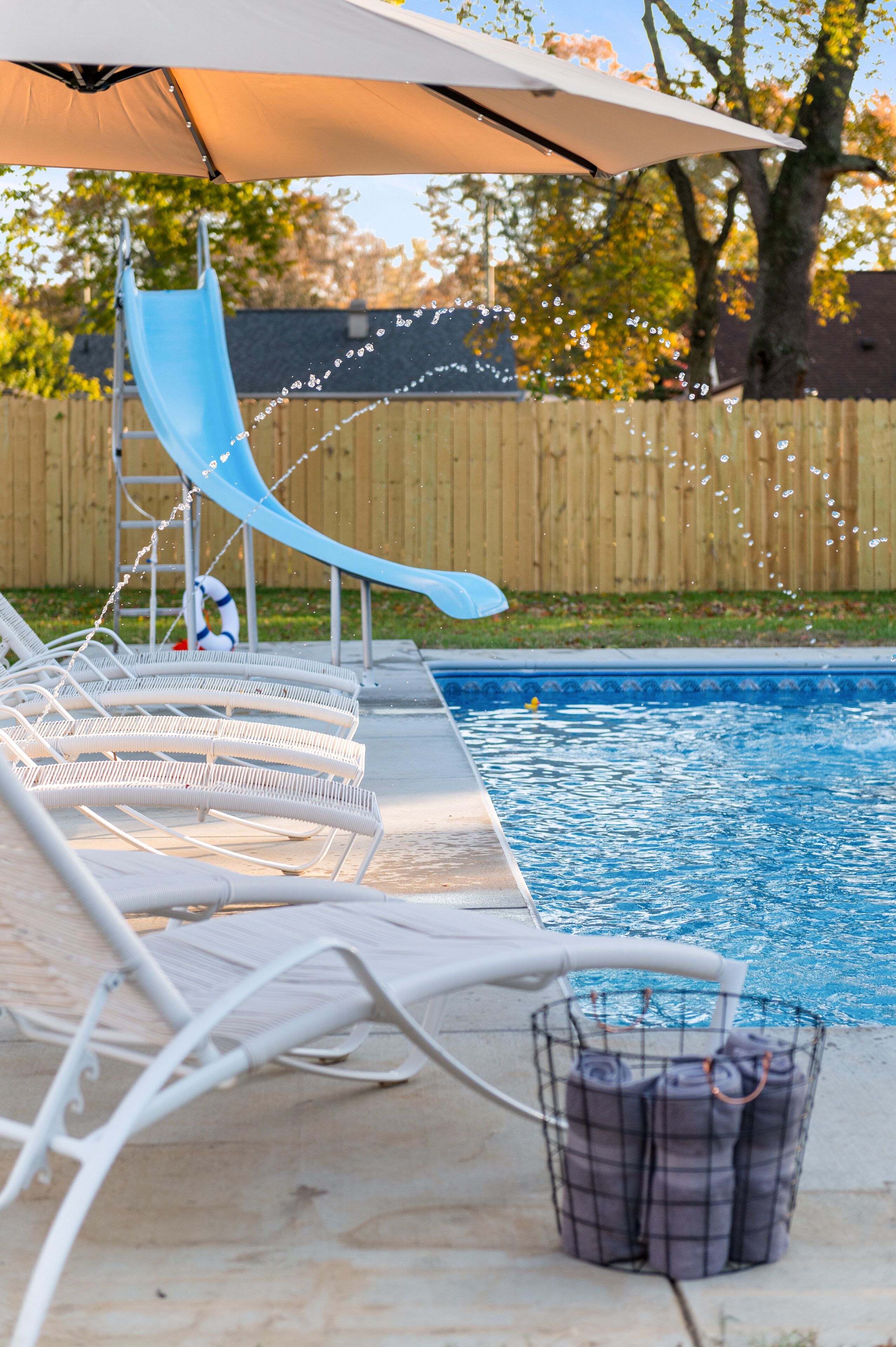 Un espace piscine équipé de chaises longues, d’un toboggan et d’un parasol.