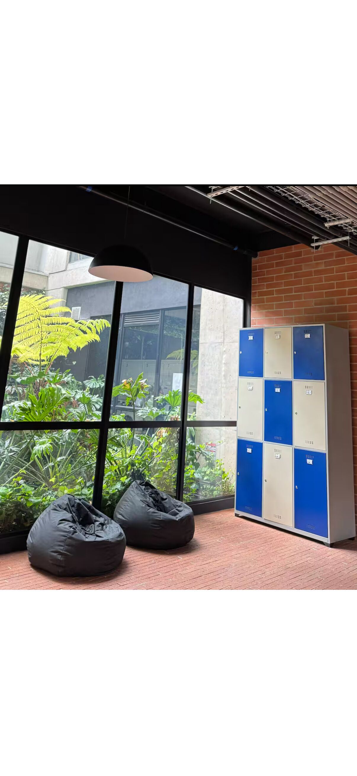 A room with large windows, a brick wall, and a set of lockers.