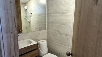 Une salle de bain moderne équipée d’une douche, de toilettes et d’un meuble-lavabo.
