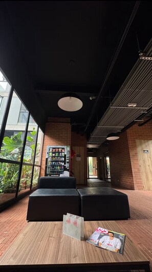 A modern indoor space with a brick wall, a vending machine, and a magazine on a table.