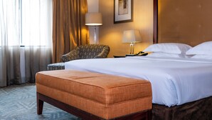 A hotel room with a large bed, a chair, a desk with a lamp, and a framed picture on the wall. - Royal Majestic Hotel (Johannesburg)