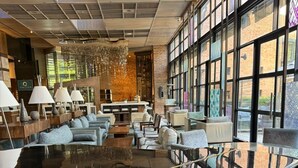 A spacious lobby with a grand piano, comfortable seating, and large windows offering views of the outside. - Royal Majestic Hotel (Johannesburg)