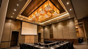 A conference room with a long table, chairs, a projector screen, and a unique ceiling design. - Royal Majestic Hotel (Johannesburg)