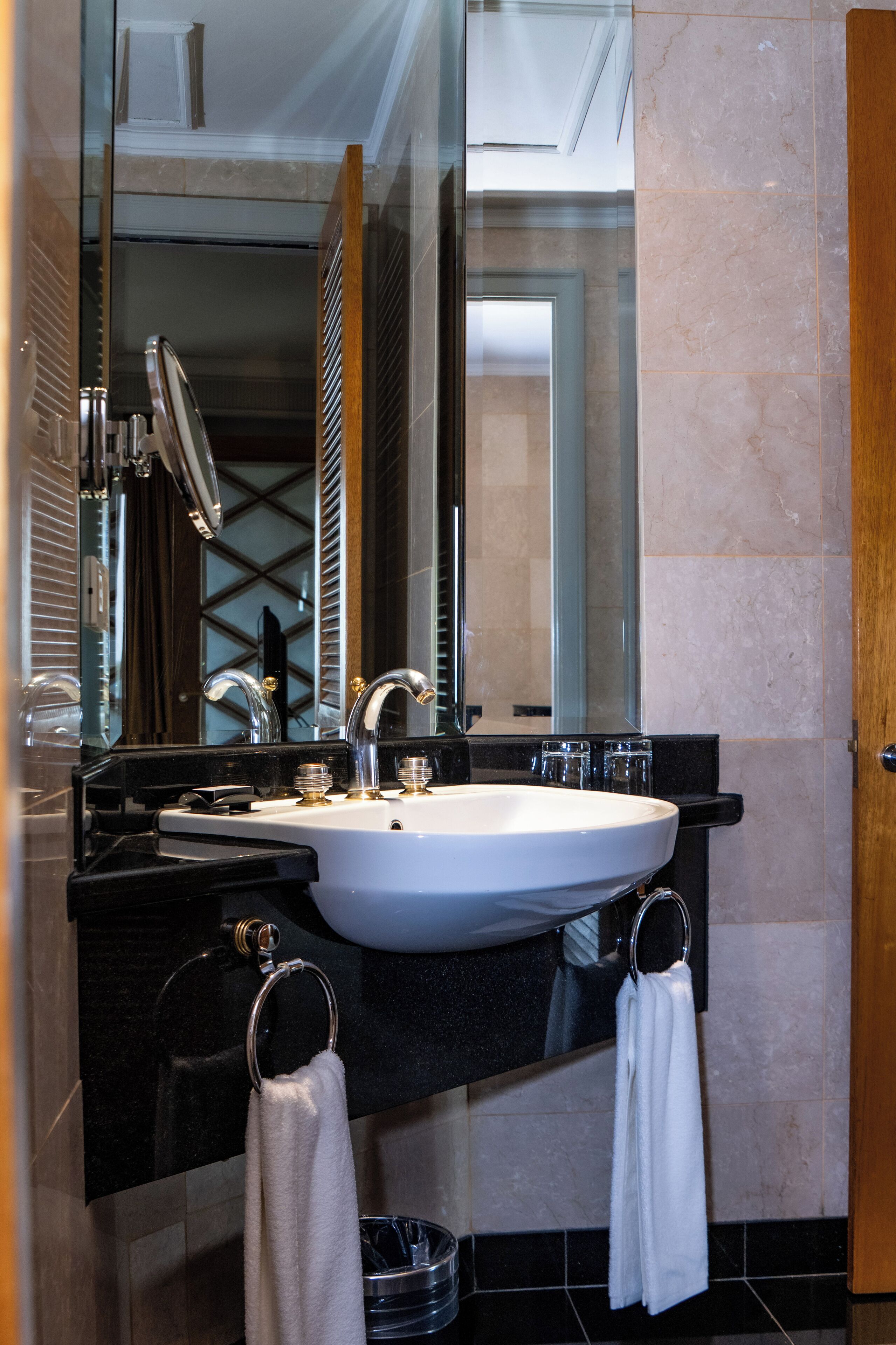 Une salle de bain moderne avec un grand miroir, un lavabo blanc et un plan de toilette noir.
