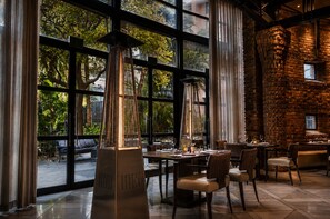 A restaurant with large windows, a brick wall, and modern furniture. - Royal Majestic Hotel (Johannesburg)