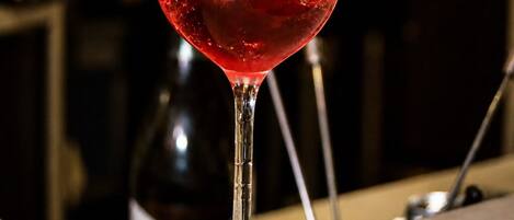Un vaso con líquido rojo y cubitos de hielo, sobre una barra.