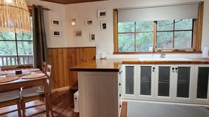 Ett mysigt kök med träskåp, ett matbord med underlägg och ett fönster med utsikt över grönområden.