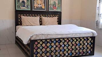 Une chambre à coucher avec un lit, un ventilateur de plafond et trois œuvres d’art encadrées accrochées au mur.