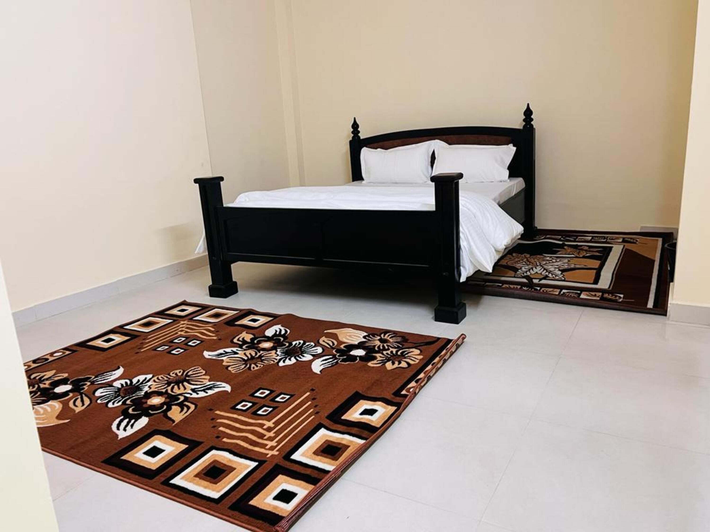 Een slaapkamer met een bed, een kamerkleed en een decoratieve vloermat.