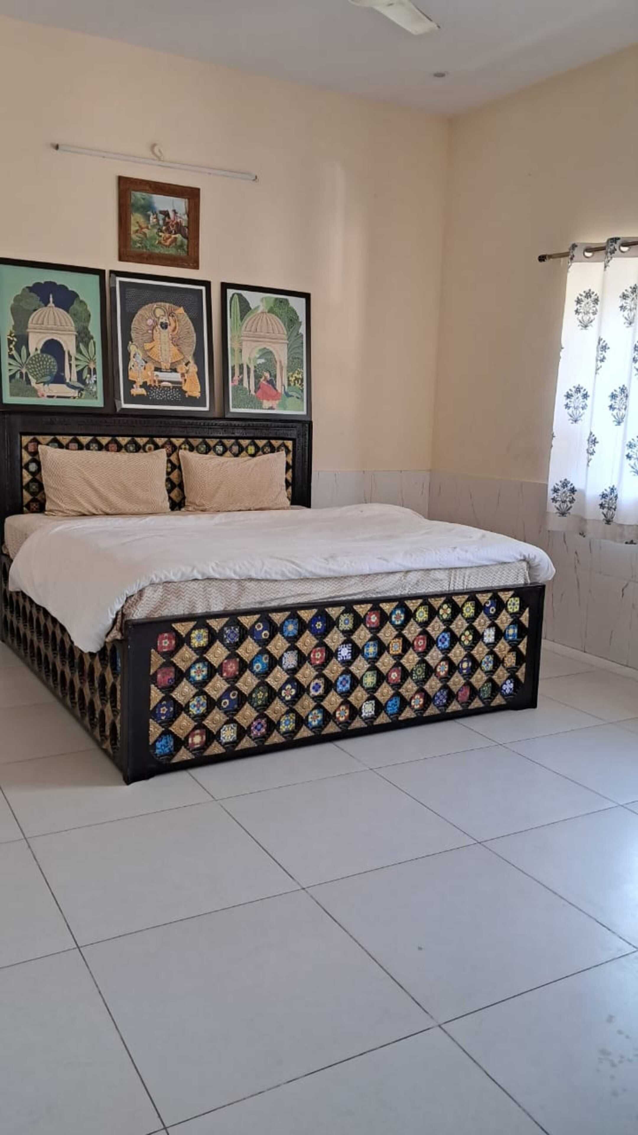 A bedroom with a bed, a ceiling fan, and framed artwork on the wall.
