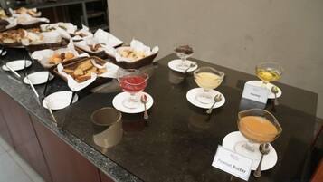 A buffet with various food items and labeled dishes, including a dessert and a beverage.