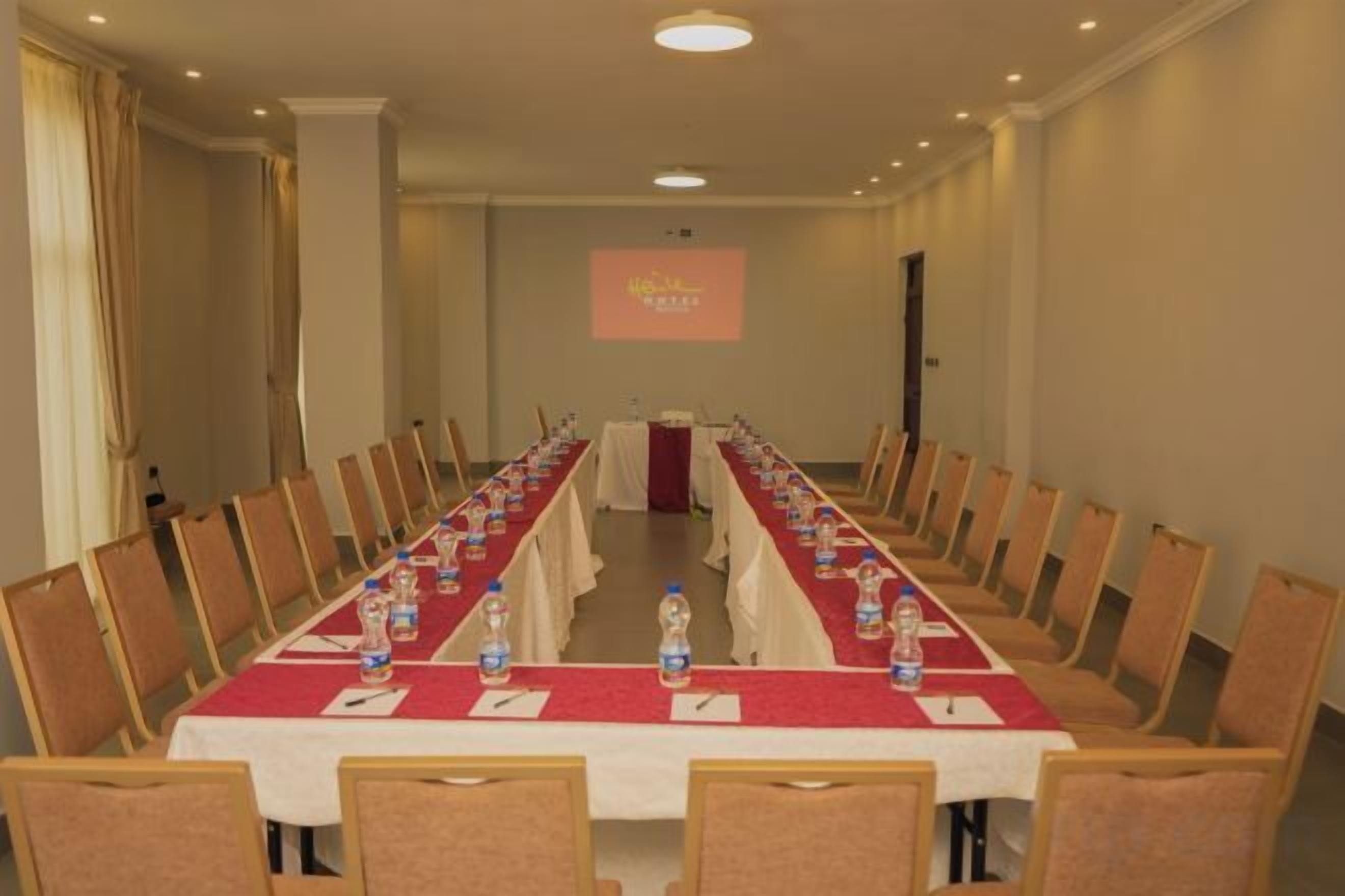 Ein Konferenzraum mit einem langen Tisch, Stühlen und einer Projektionsleinwand.