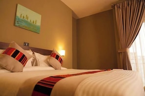 Una habitación de hotel con una cama, almohadas, un cuadro en la pared y una lámpara.