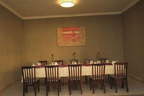 Comedor con una larga mesa dispuesta para seis personas, rodeada de seis sillas, y un tapiz decorativo en la pared.