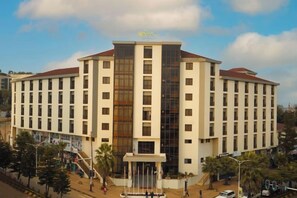 A multi-story hotel with a central courtyard, a fountain, and a flat roof.