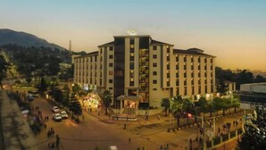 A multi-story hotel with a central courtyard, surrounded by trees and a parking area. - Haile Hotel Wolaita (Sodo)