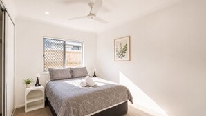 A bedroom with a bed, a ceiling fan, a window with a view, and a framed picture on the wall. - Sparkling New Home - Suburban Charms Awaits (Park Ridge)
