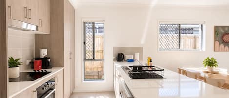 Cocina moderna con una isla central, horno empotrado y puerta corrediza de vidrio hacia un patio.
