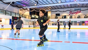 An indoor ice skating rink with a sign that reads 'SKATE Paradise'.