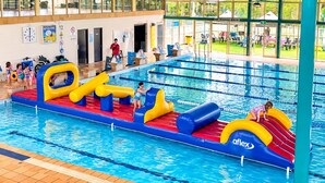 An indoor swimming pool with inflatable play structures and a tiled deck area. - Sparkling New Home - Suburban Charms Awaits (Park Ridge)