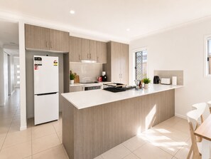 A modern kitchen with a central island, white cabinetry, and a built-in oven. - Sparkling New Home - Suburban Charms Awaits (Park Ridge)