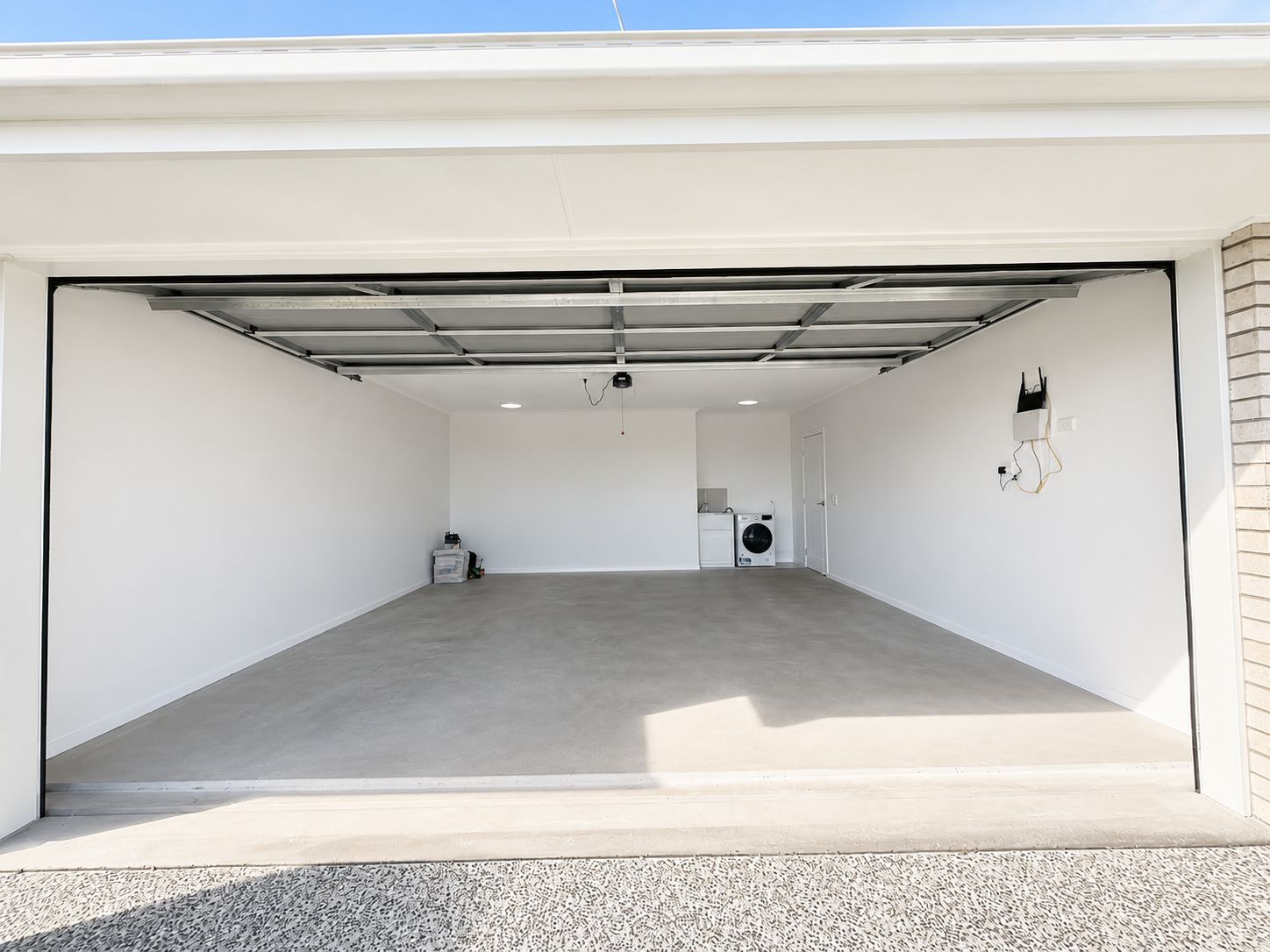 Eine saubere, leere Garage mit Betonboden, einer Waschmaschine und einem Trockner.