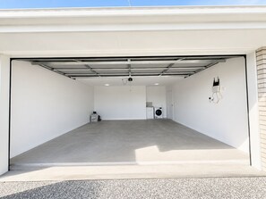 A clean, empty garage with a concrete floor, a washing machine, and a dryer. - Sparkling New Home - Suburban Charms Awaits (Park Ridge)