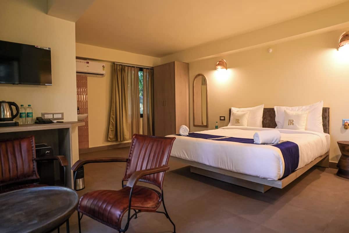 Une chambre d’hôtel avec un lit, un bureau, une chaise, une télévision et une fenêtre avec des rideaux.