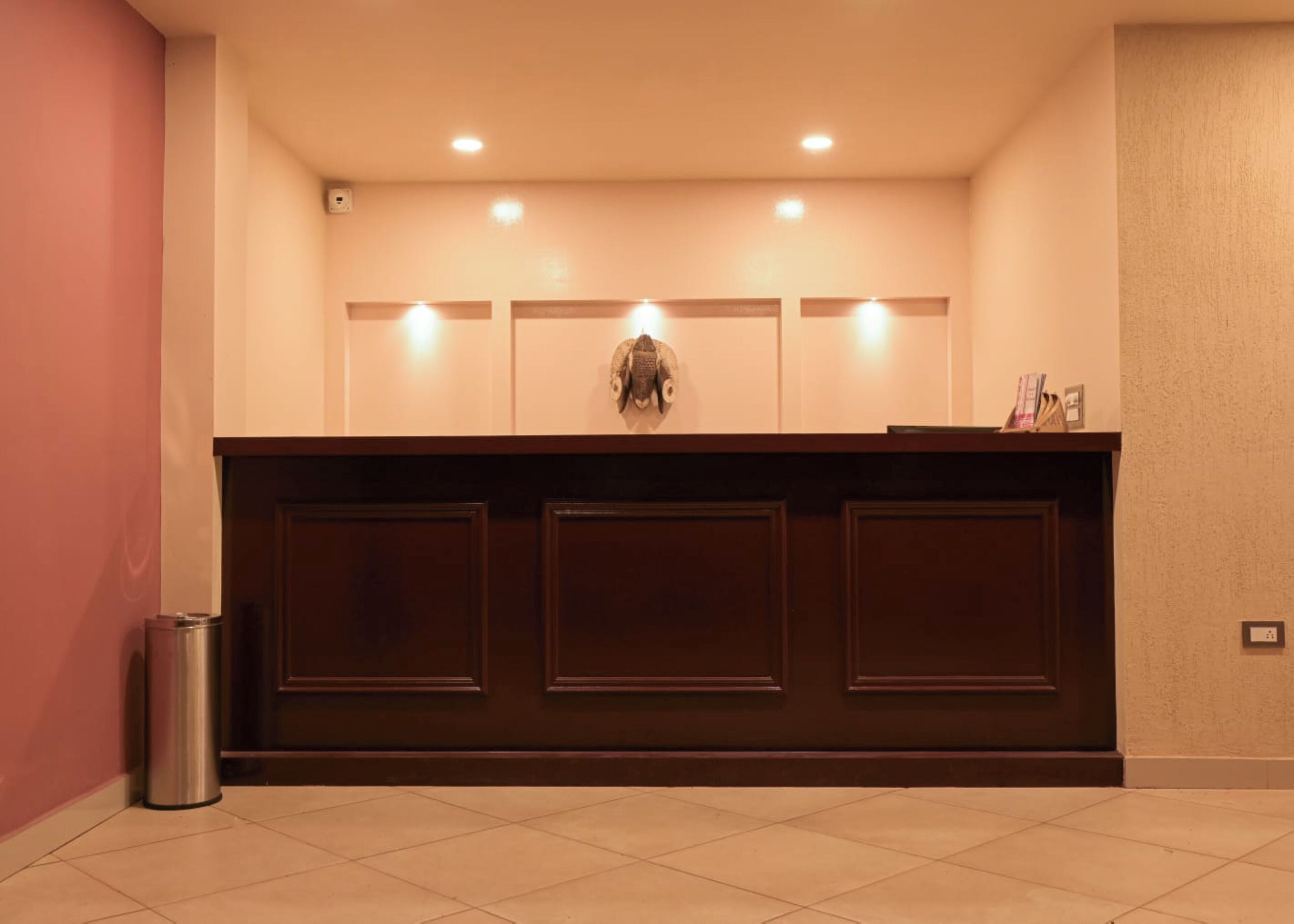 A reception desk with three panels, a trash bin, and a wall-mounted light fixture.