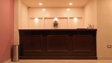 A reception desk with three panels, a trash bin, and a wall-mounted light fixture.