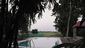 Una piscina con vista su un prato verde e alberi sullo sfondo.
