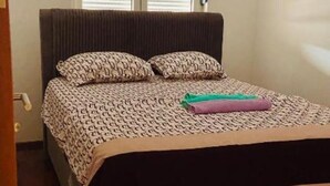 Une chambre à coucher avec un lit, une fenêtre avec des stores, une porte et un petit tapis.