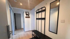 Un pasillo con techo de madera, un banco, un perchero y un espejo.