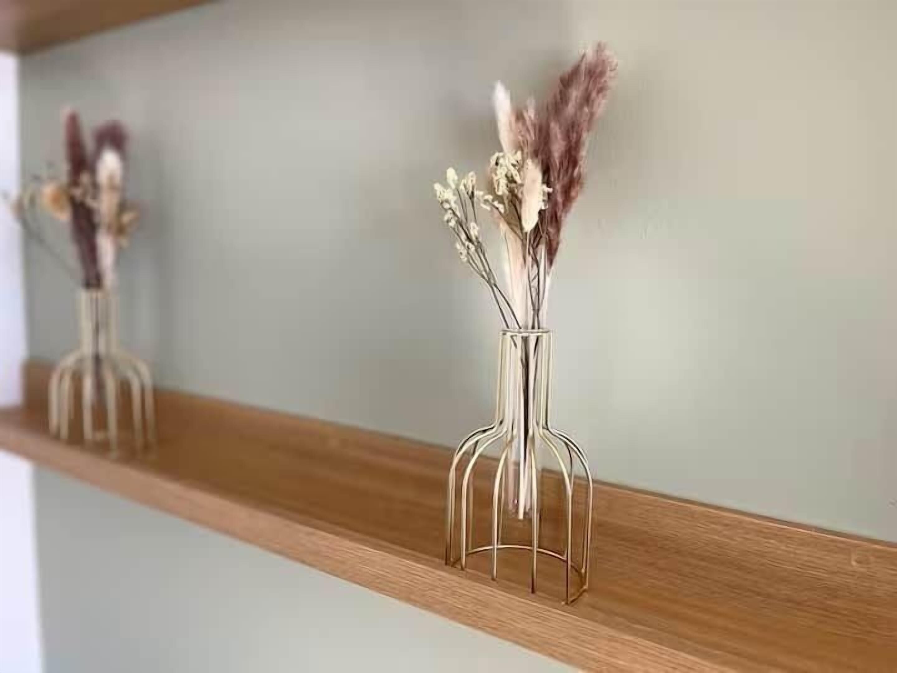 Una estantería de madera con dos jarrones de vidrio que contienen flores secas.