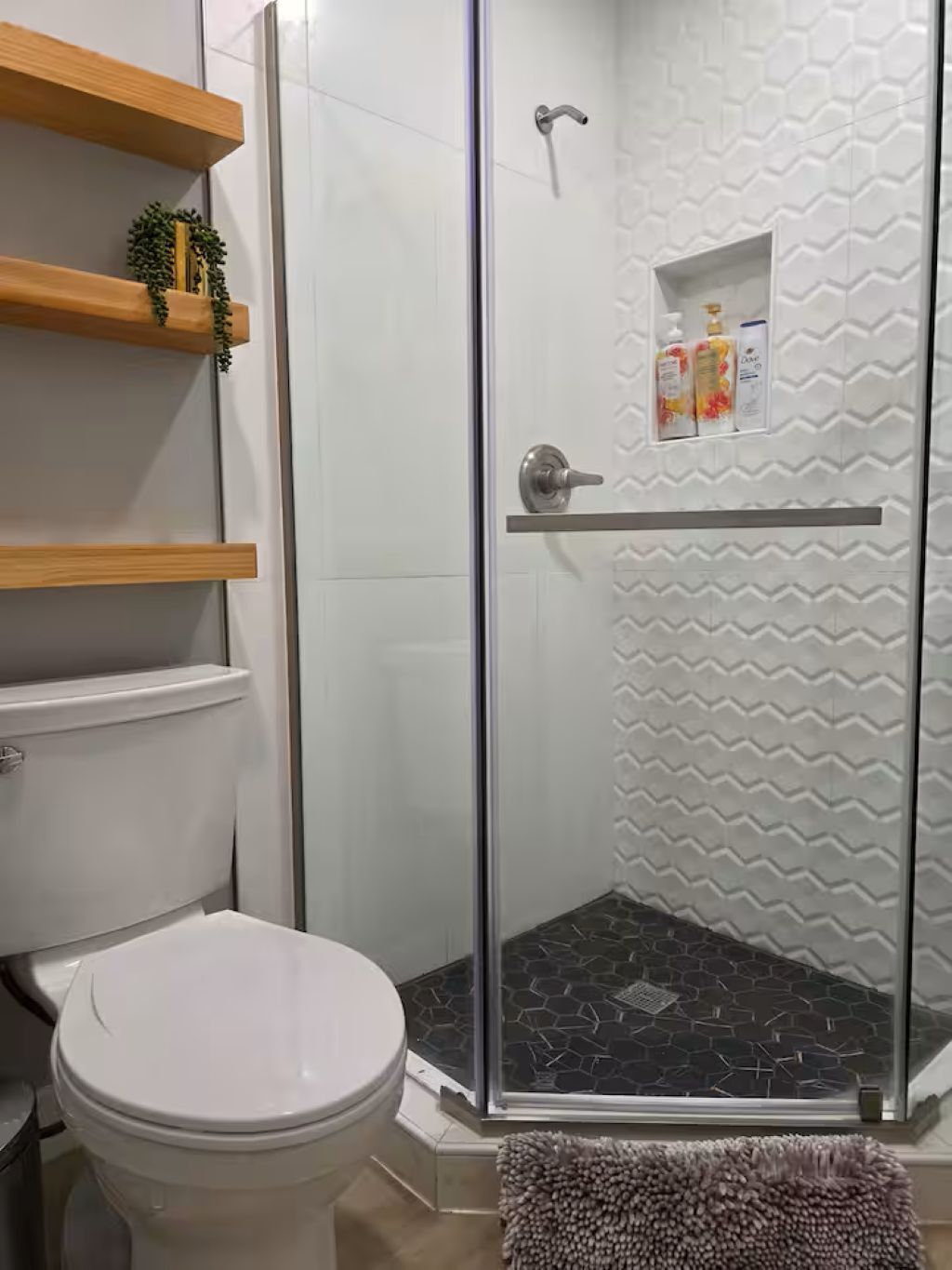 Ein Badezimmer mit Toilette, einer Dusche mit Glastür und Ablage für Toilettenartikel.