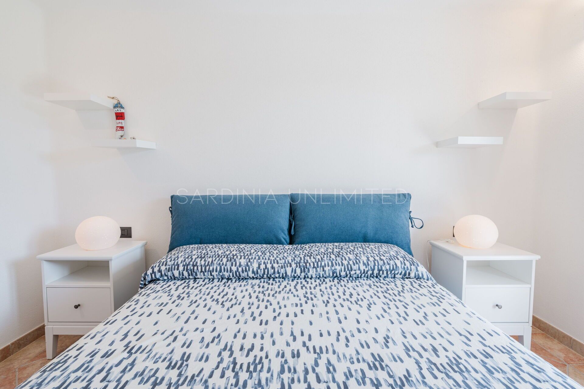 Una camera da letto con un letto, due comodini e una mensola a muro.