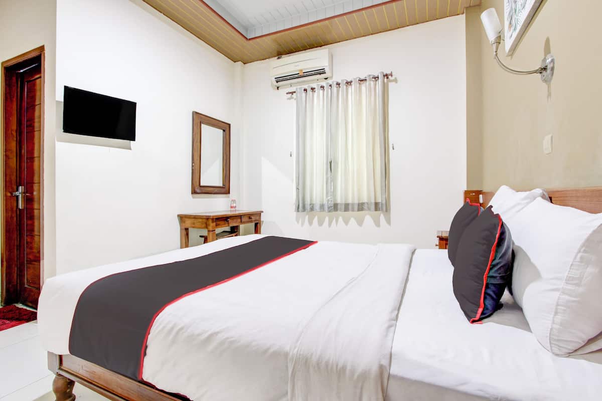 A neatly made bed with a black and white bedspread, a wooden headboard, and a bedside table with a lamp.