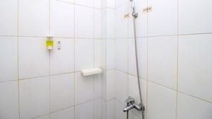 Una doccia con soffione a mano, rubinetto a parete, dispenser di sapone e una piccola mensola.
