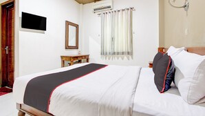 Un letto rifatto con cura, con copriletto bianco e nero, una testiera in legno e un comodino con una lampada.